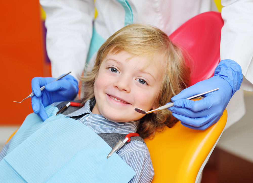 Smiling blond boy in a yellow dental chair during a checkup